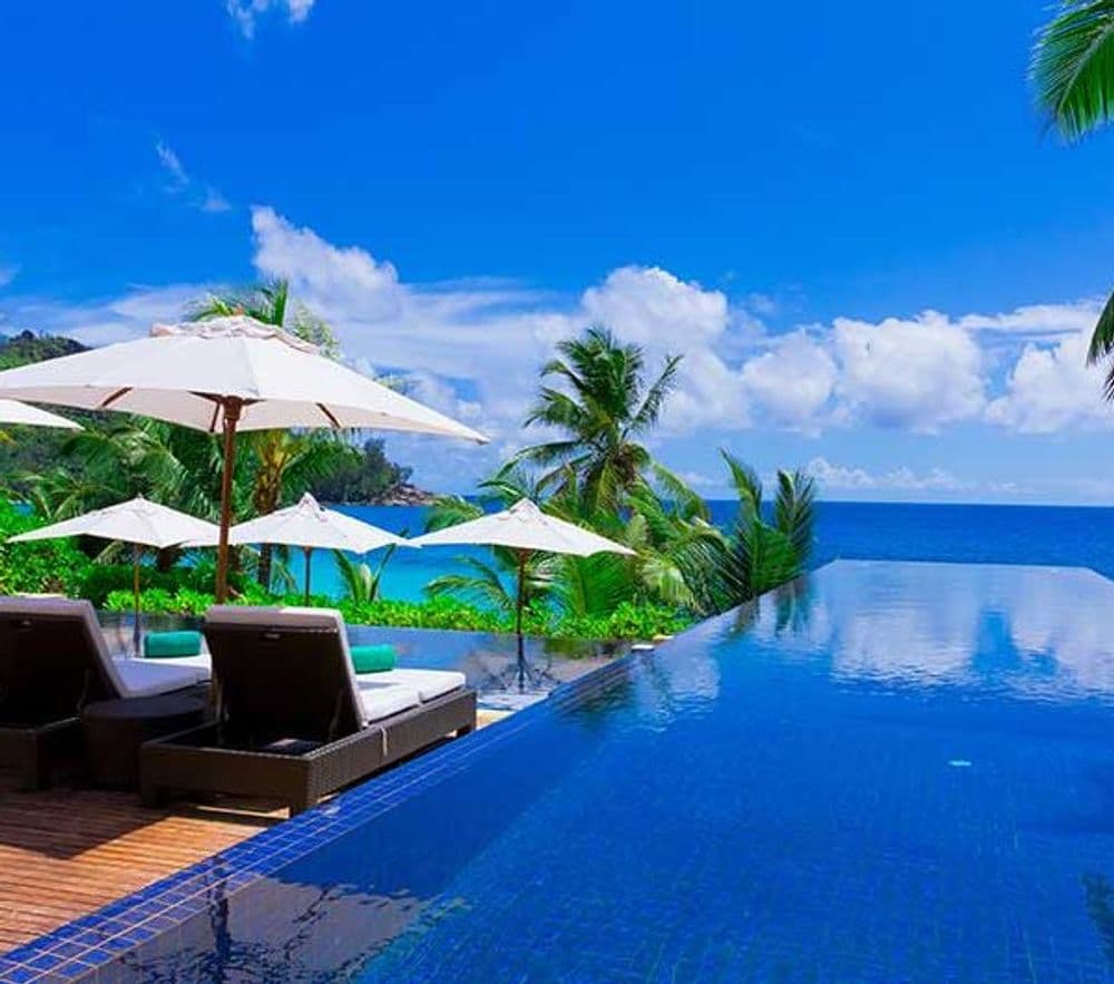 Luxury resort featuring infinity pool, sun loungers, and tropical ocean views.