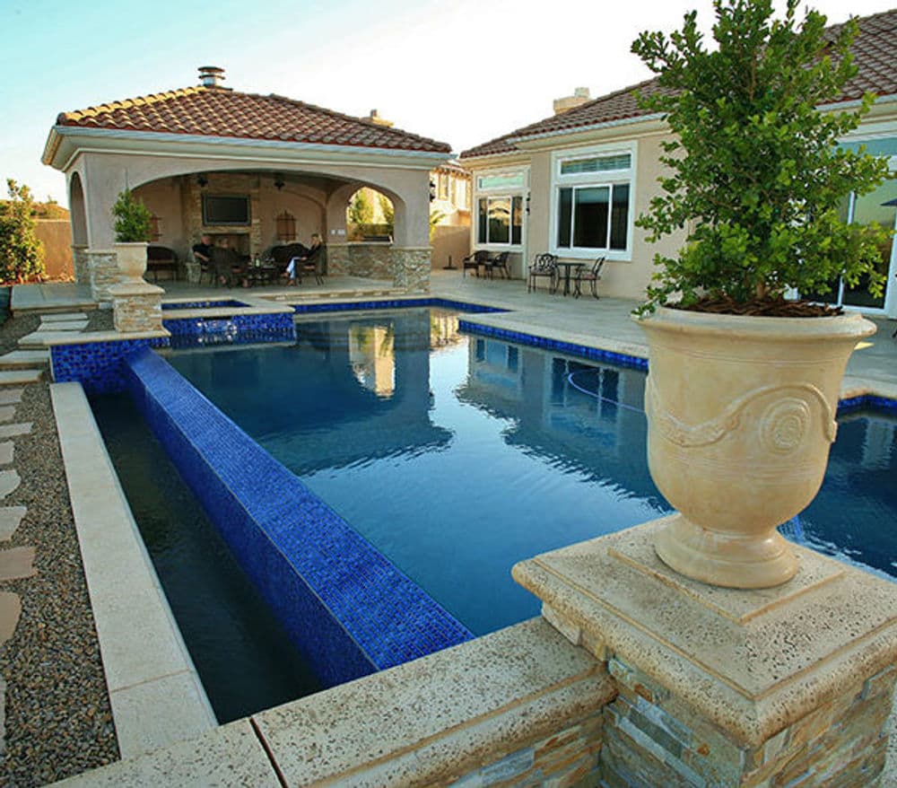 Elegant backyard pool with stone accents and a shaded pergola for relaxation.