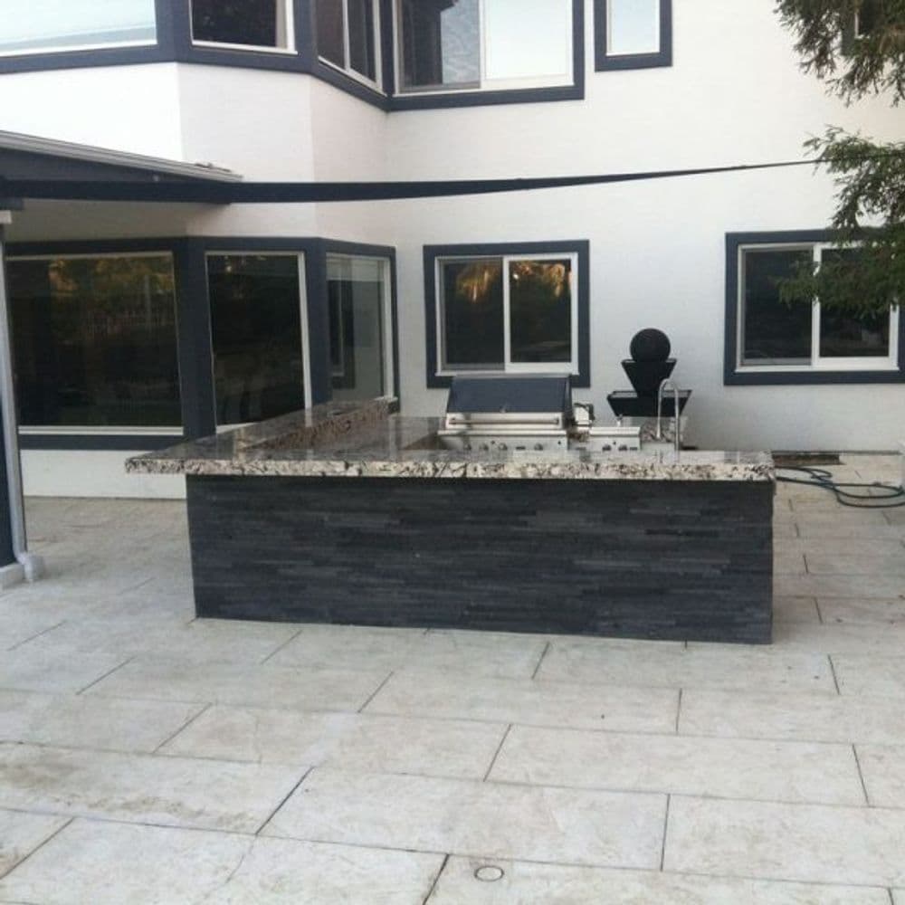 Modern outdoor kitchen with granite countertop and sleek stone base in a contemporary home.