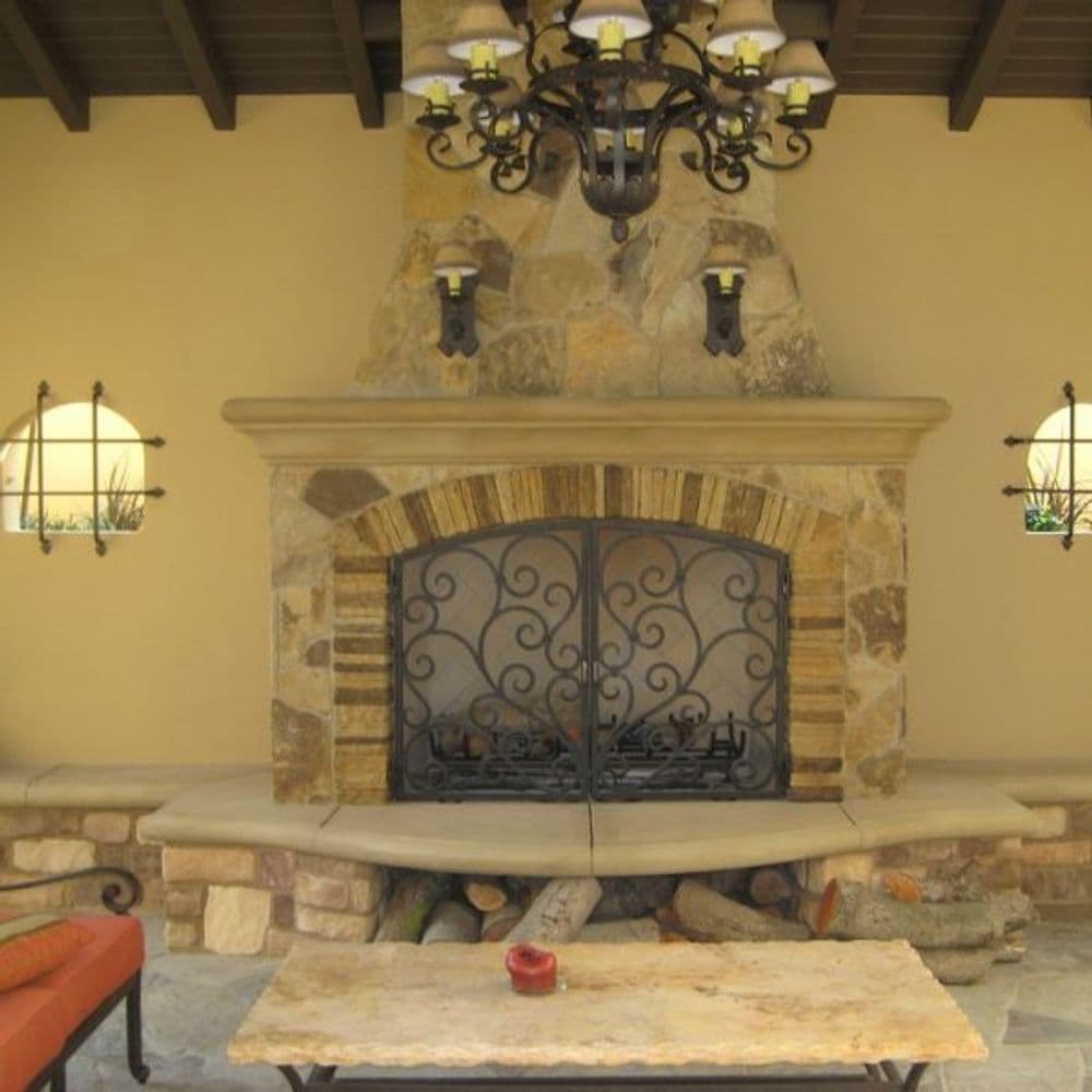Elegant outdoor living space featuring a stone fireplace, wrought iron details, and chandelier.